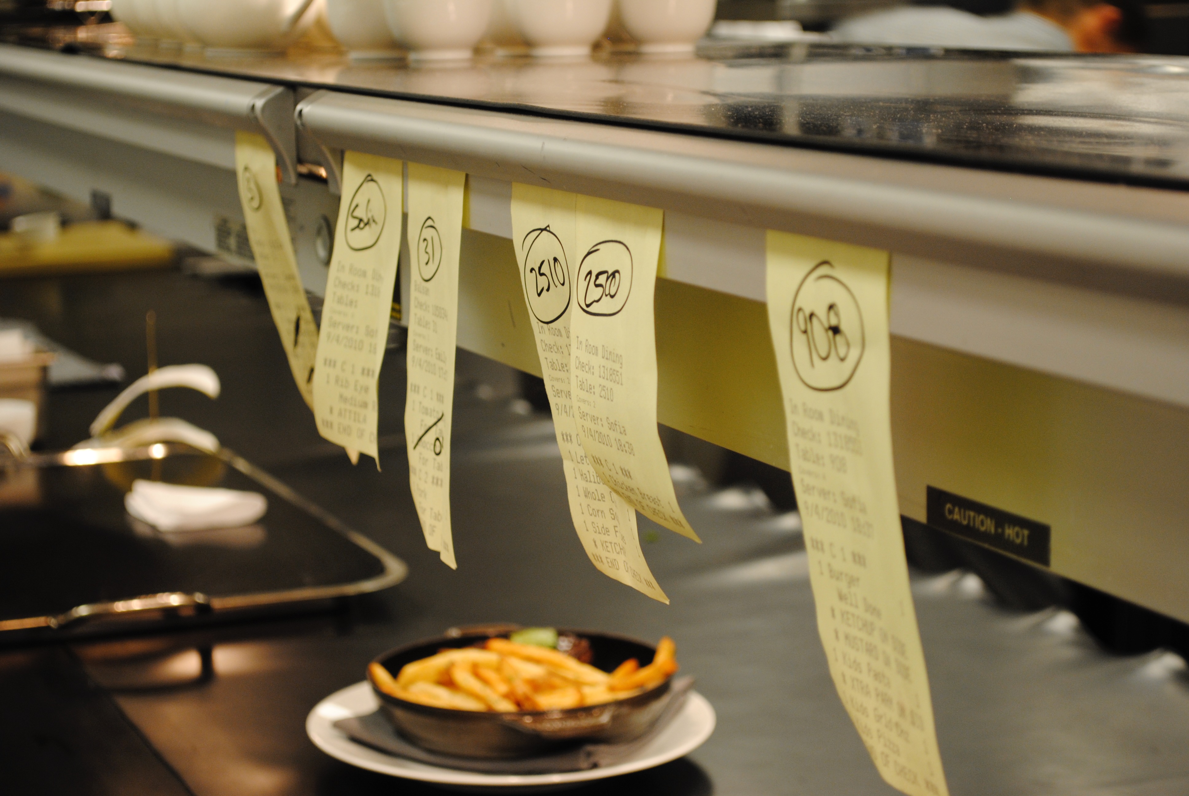 Kitchen tickets on a rail with a plate of fries